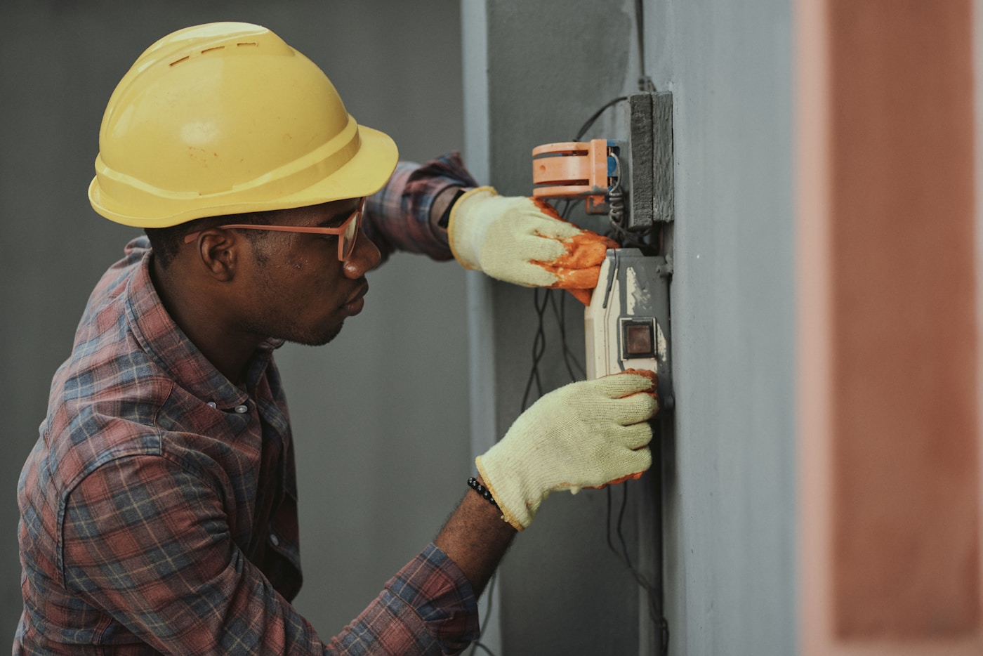 An electrician in a hard hat working on an electrical panel