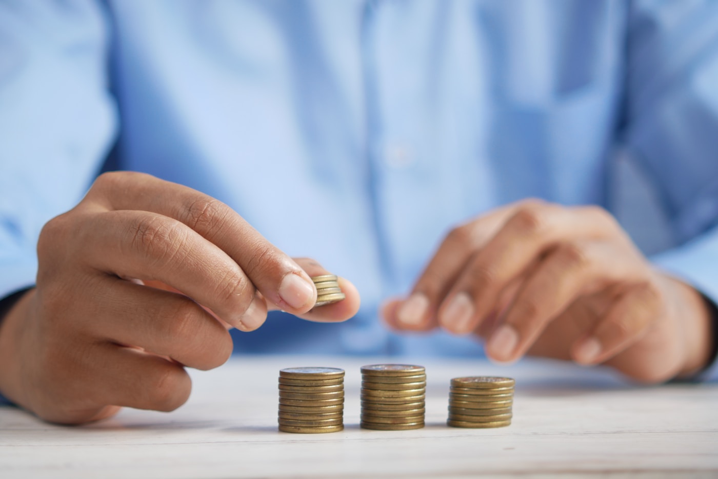 Hands stacking coins into growing piles, saving up for study costs